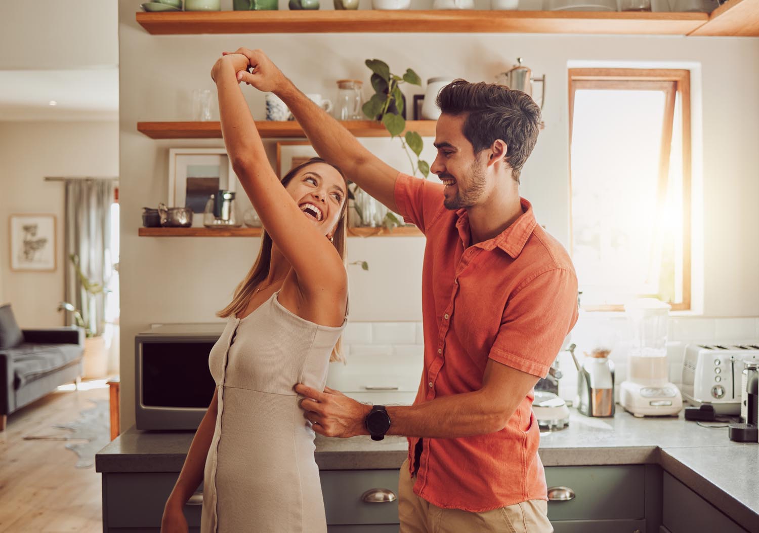 A joyful couple dances together in a bright kitchen, promoting a healthy lifestyle and happiness.